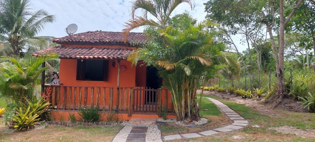JaguaripeCasa temporada jaguaripe bahia toca do guaiamum的一座带围栏和棕榈树的橙色小房子