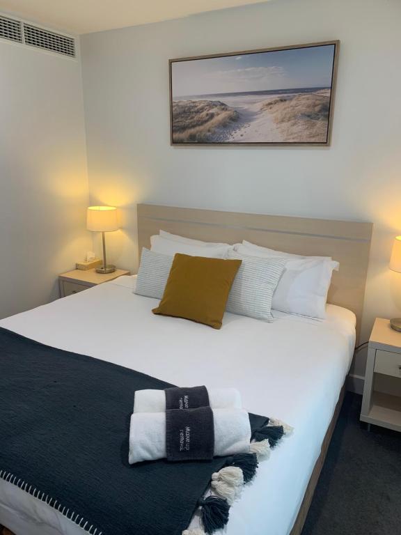 格莱内尔格Pier 108 Glenelg的卧室配有带毛巾的大型白色床