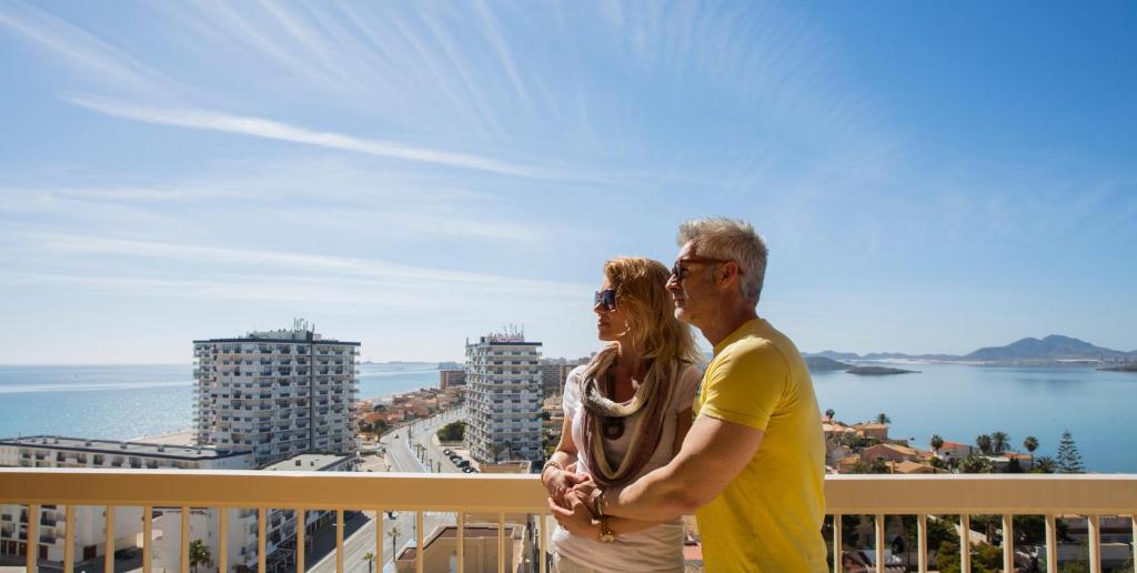 拉曼加戴尔马尔梅纳Poseidon La Manga Hotel & Spa - Designed for Adults的男人和女人站在一个俯瞰大海的阳台