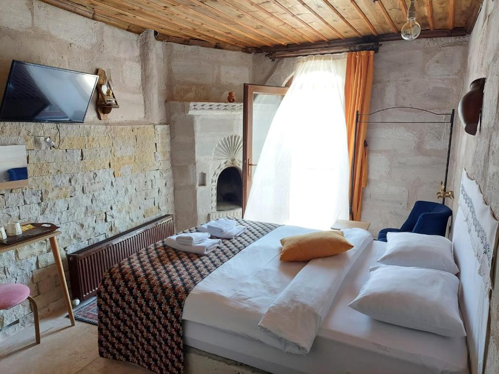 内夫谢希尔Duru Cappadocia Stone House的一间卧室设有一张床、一台电视和一个窗口。