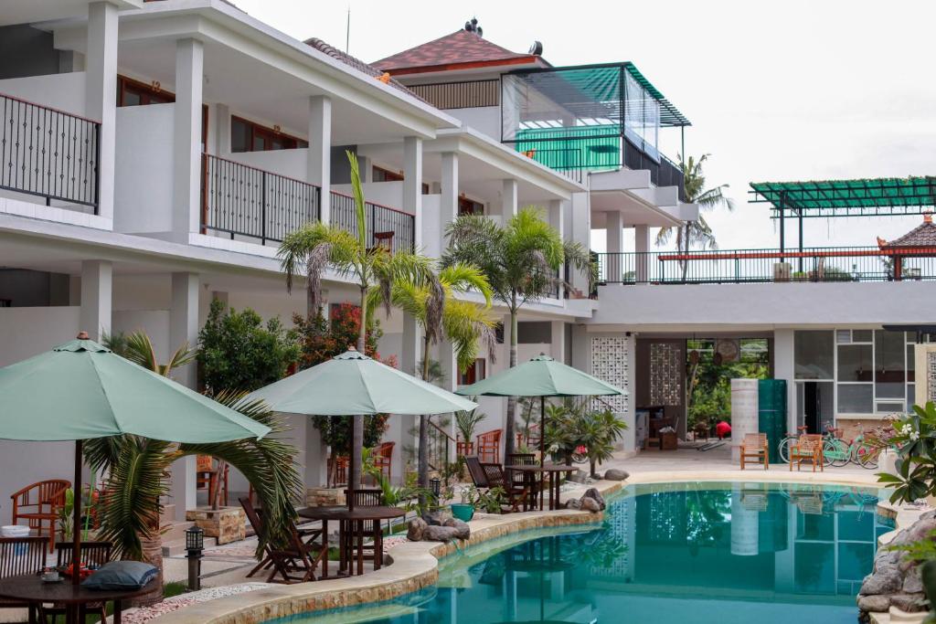 吉利阿尔De Padma Gili Air的酒店设有一个游泳池、桌子和遮阳伞