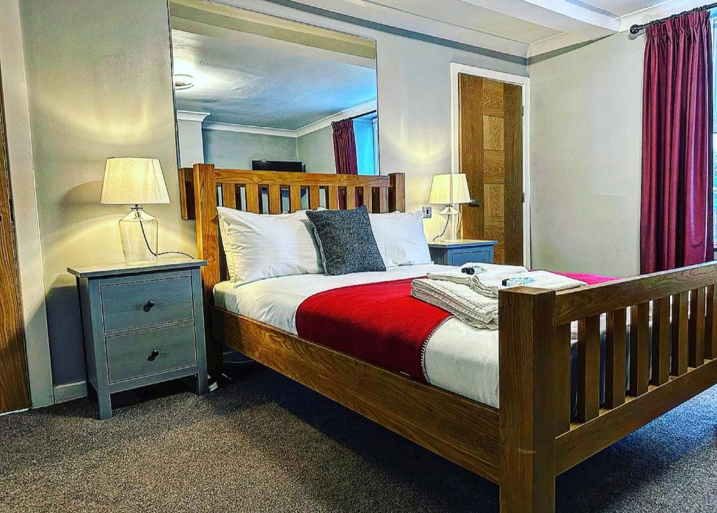 乔利The Hinds Head Hotel的一间卧室配有一张木床、两个床头柜和两个灯。