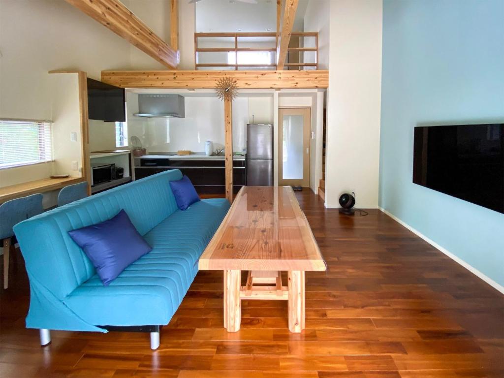 FukaiYonehara Beach Stay LUANA - Vacation STAY 38711v的客厅配有蓝色的沙发和木桌