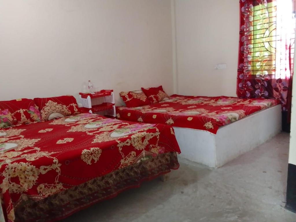 库亚加塔Kuakata Hotel & Resort的宿舍间的两张床,配有红色毯子和窗户