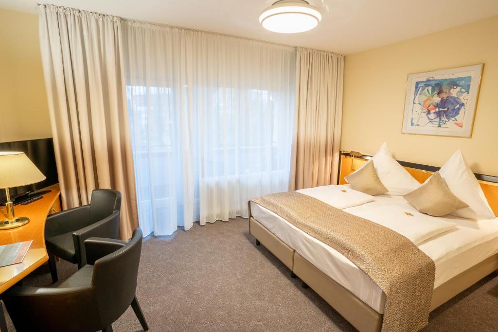 博登斯边的拉多夫采尔斯塔德花园酒店的配有一张床、一张书桌和一扇窗户的酒店客房