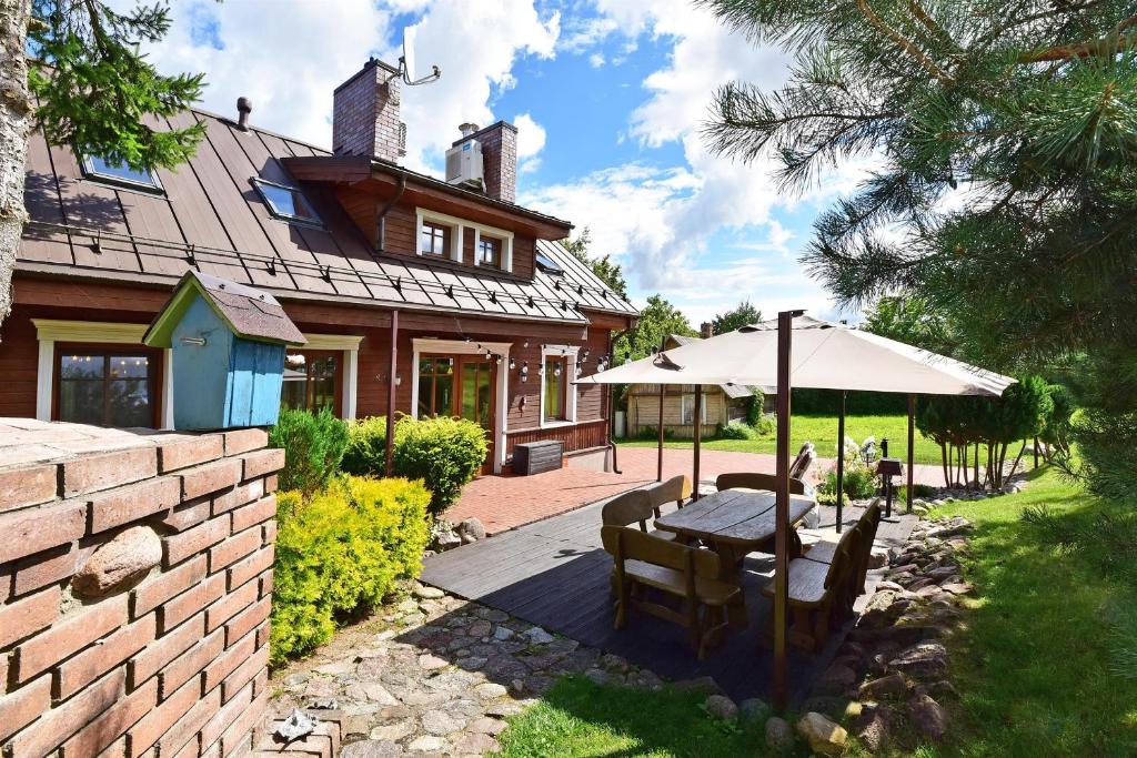 特拉凯Spa Villa Trakai的房屋前设有带桌子和遮阳伞的天井。