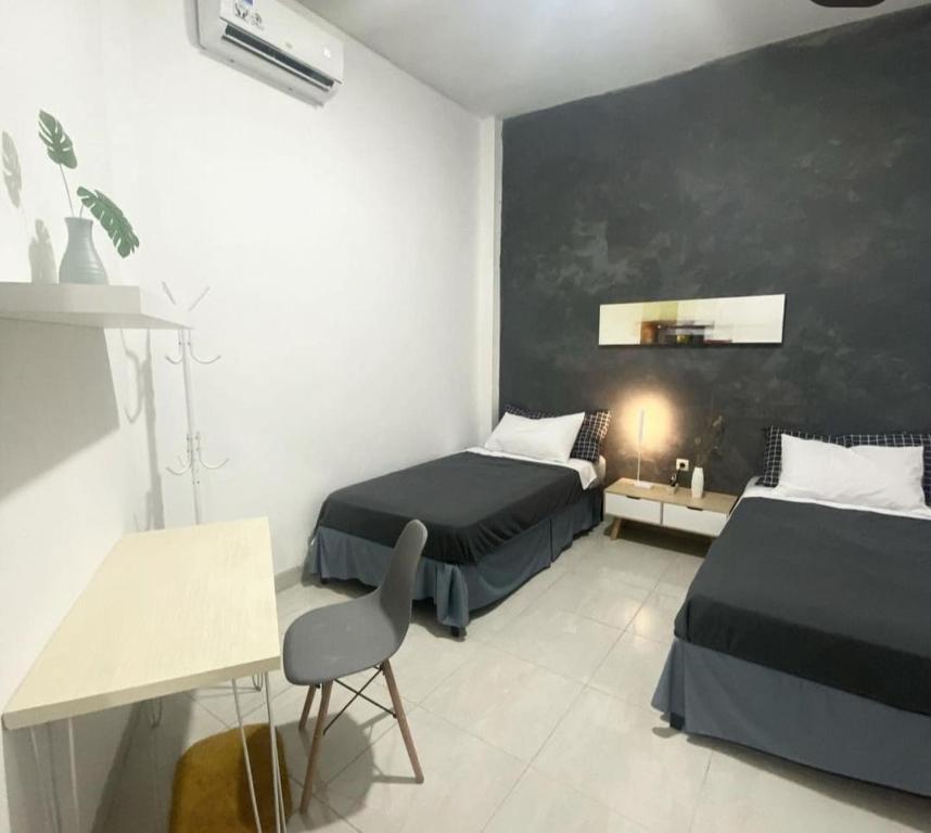 梭罗Choko Guest House的一间卧室配有两张床、一张桌子和一把椅子