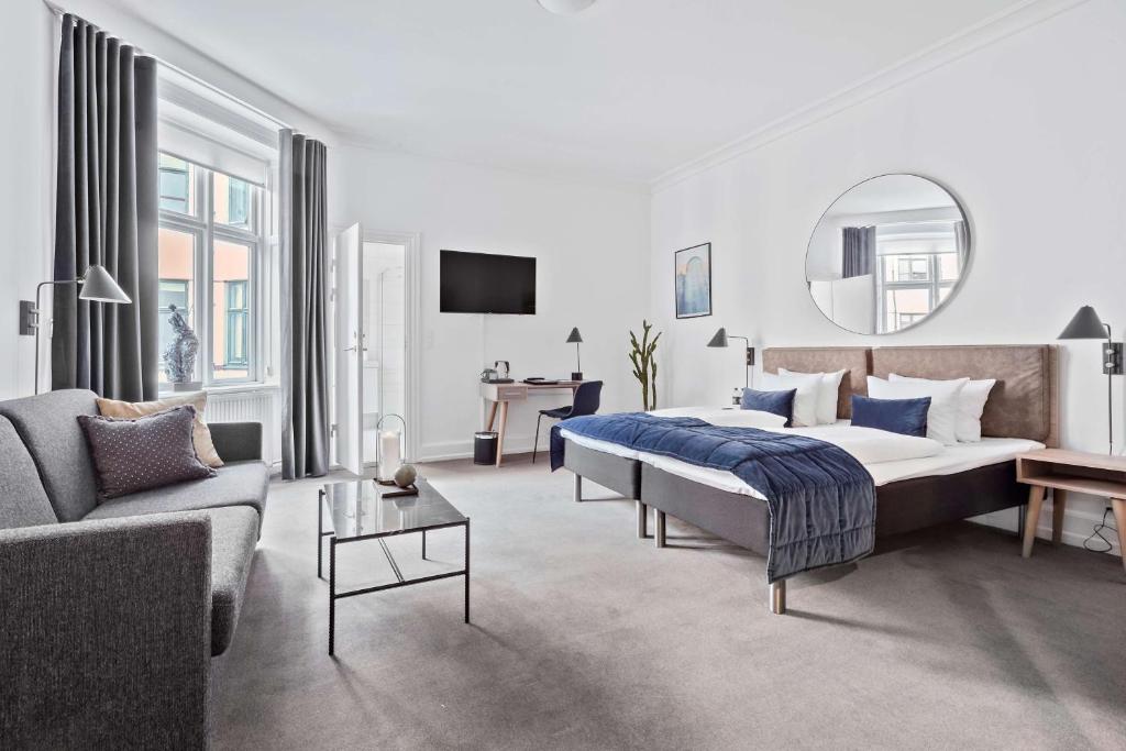 哥本哈根赫本伦贝斯特韦斯特酒店的一间卧室配有一张床、一张沙发和一面镜子