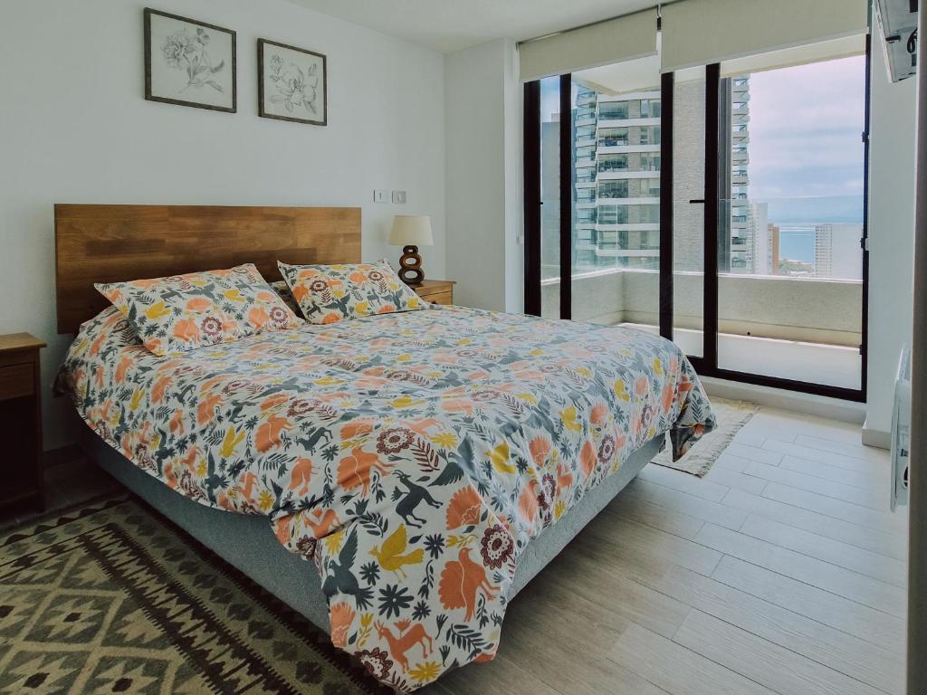 瓦尔帕莱索Departamento en Costas de Montemar, a pasos de la playa, con Vista al Mar, Piscina y GYM的一间卧室配有一张带五颜六色棉被的床