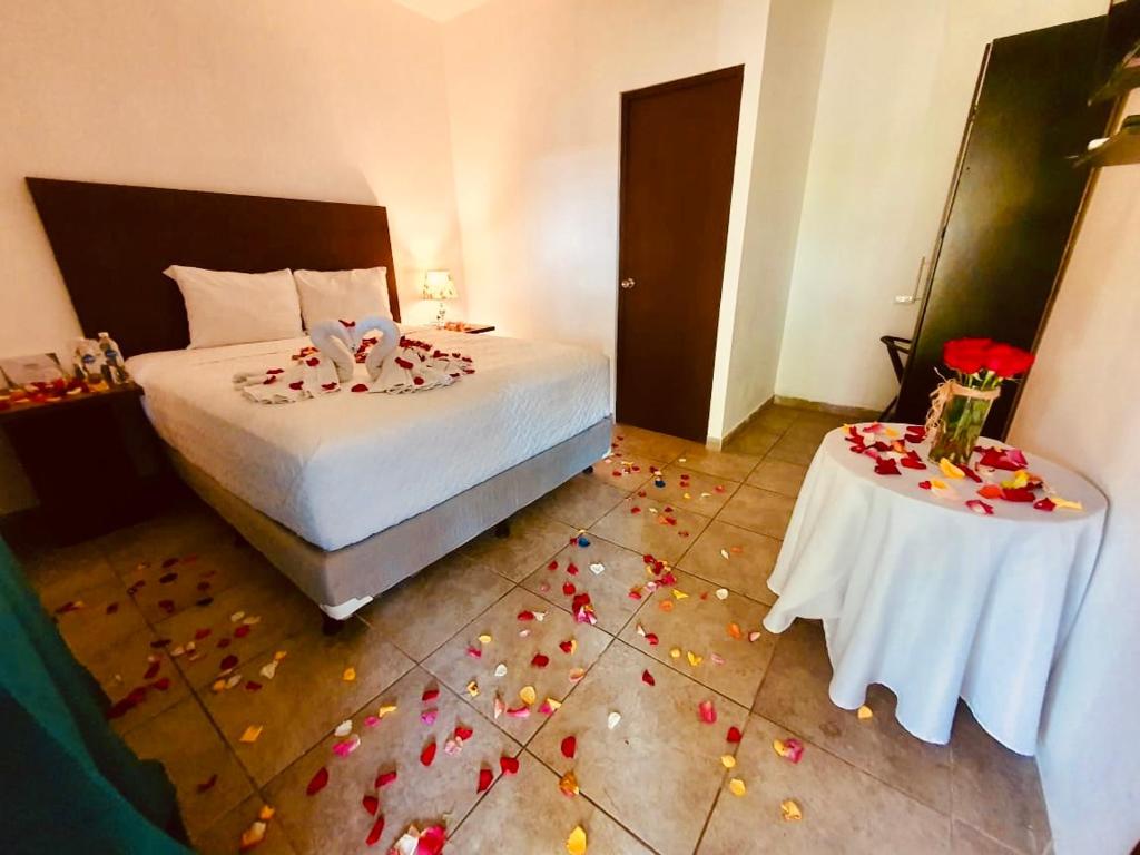 SuchitotoHotel Jardin De Las Marias的卧室配有一张床和一张带鲜花的桌子,位于地板上