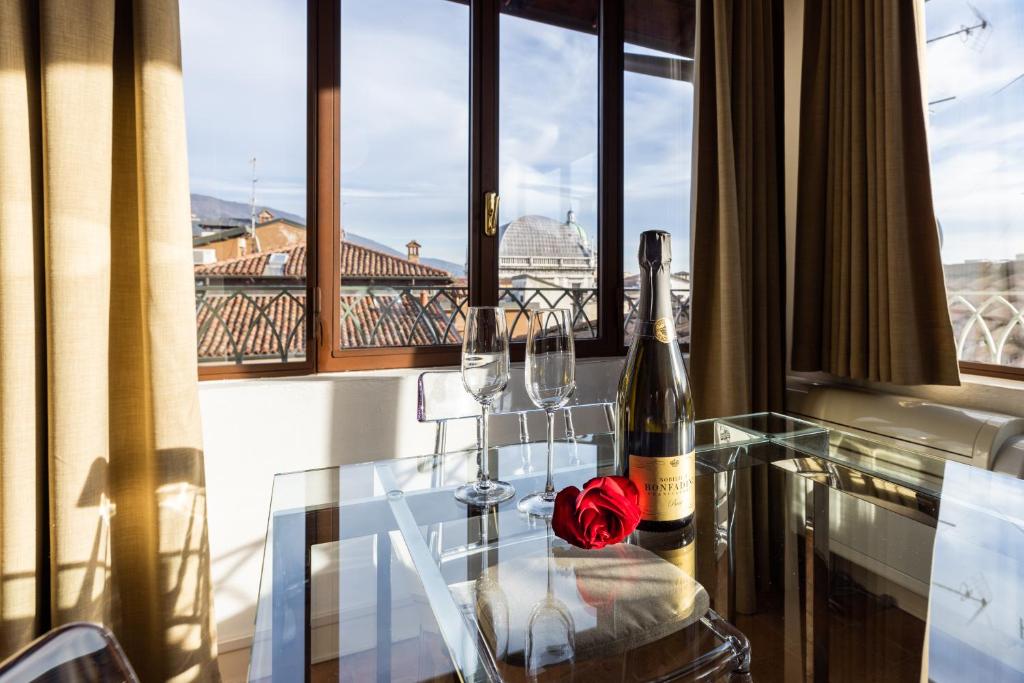 布雷西亚阿尔塔纳城市之家公寓的一张玻璃桌,上面放着两瓶葡萄酒和玫瑰
