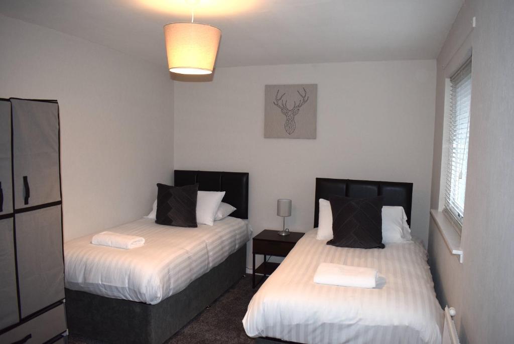 福尔柯克Kelpies Serviced Apartments- Cromwell Apt的一间卧室配有两张床和一盏灯