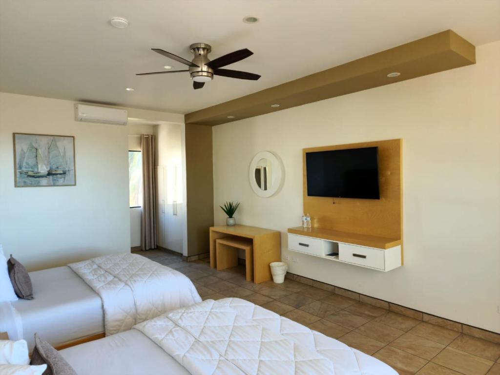 恩塞纳达港Hotel Paraiso Las Palmas的一间卧室配有两张床和一台平面电视