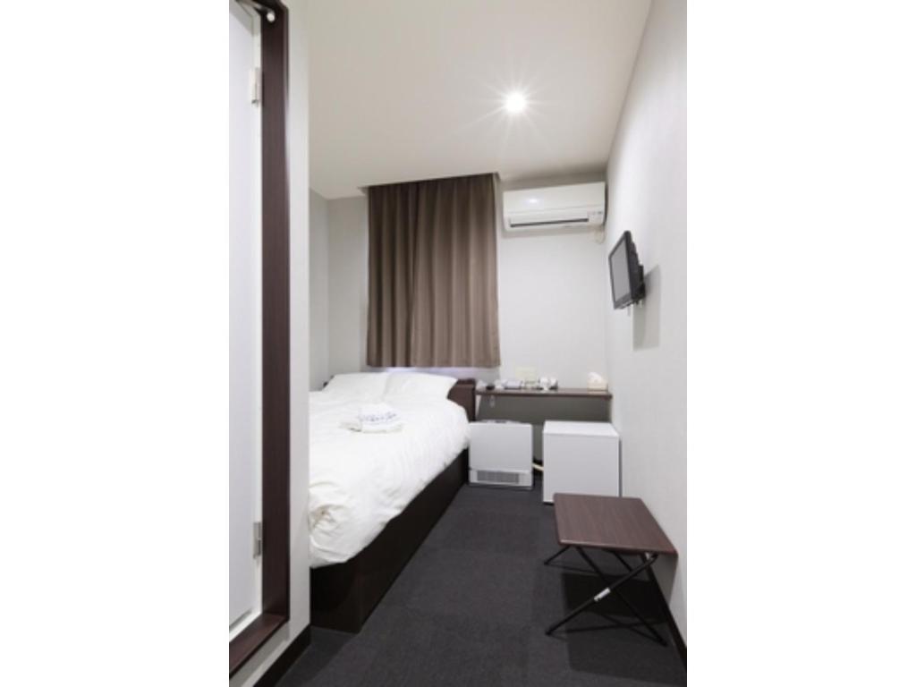 草津Kusatsu Onsen 326 Yamanoyu Hotel - Vacation STAY 10349v的酒店客房配有一张床铺和一张桌子。
