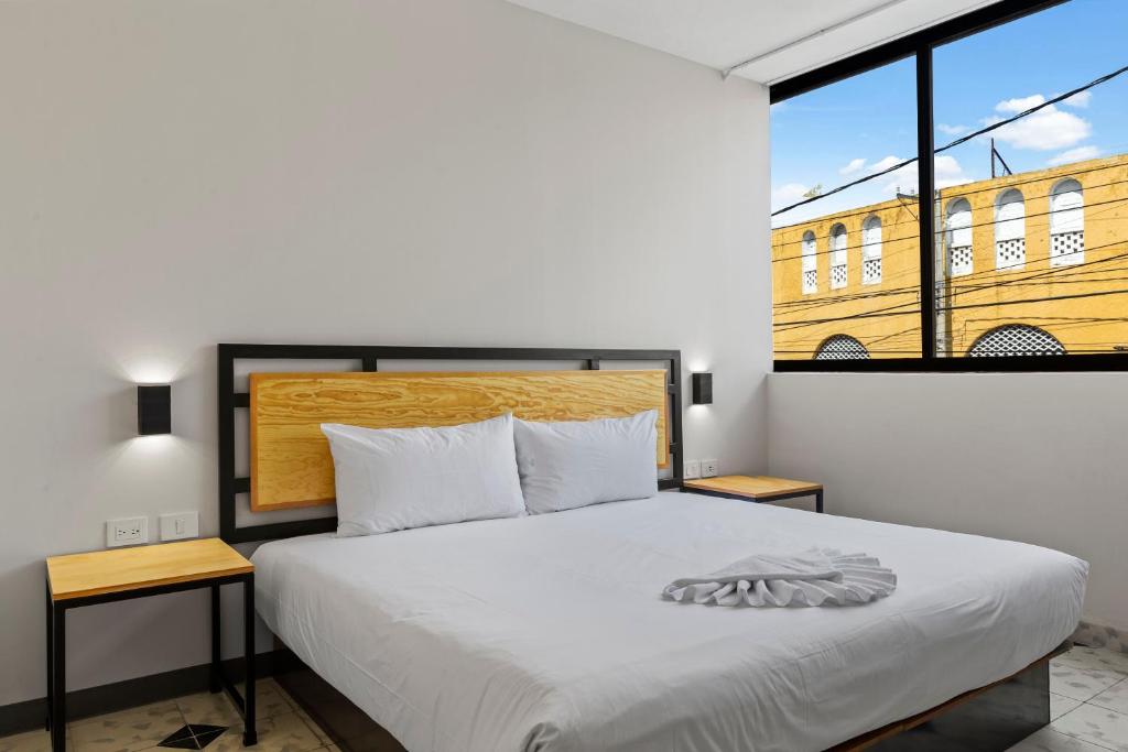 梅里达Suites Reforma by HomiRent的一间卧室设有一张床和一个大窗户