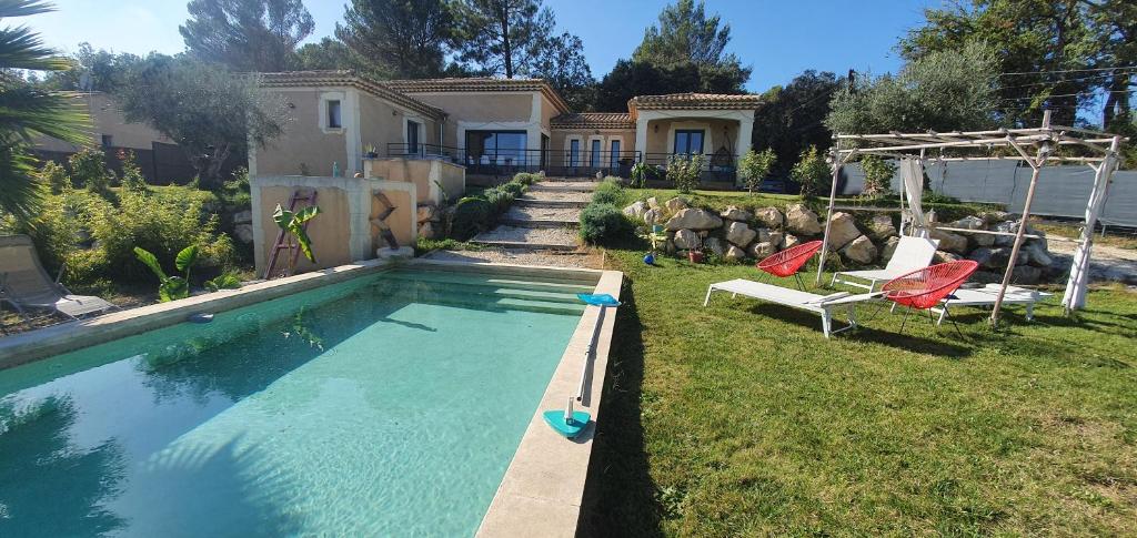 Saint-AlexandreSuperbe villa avec piscine的一个带两把椅子的游泳池以及一座房子