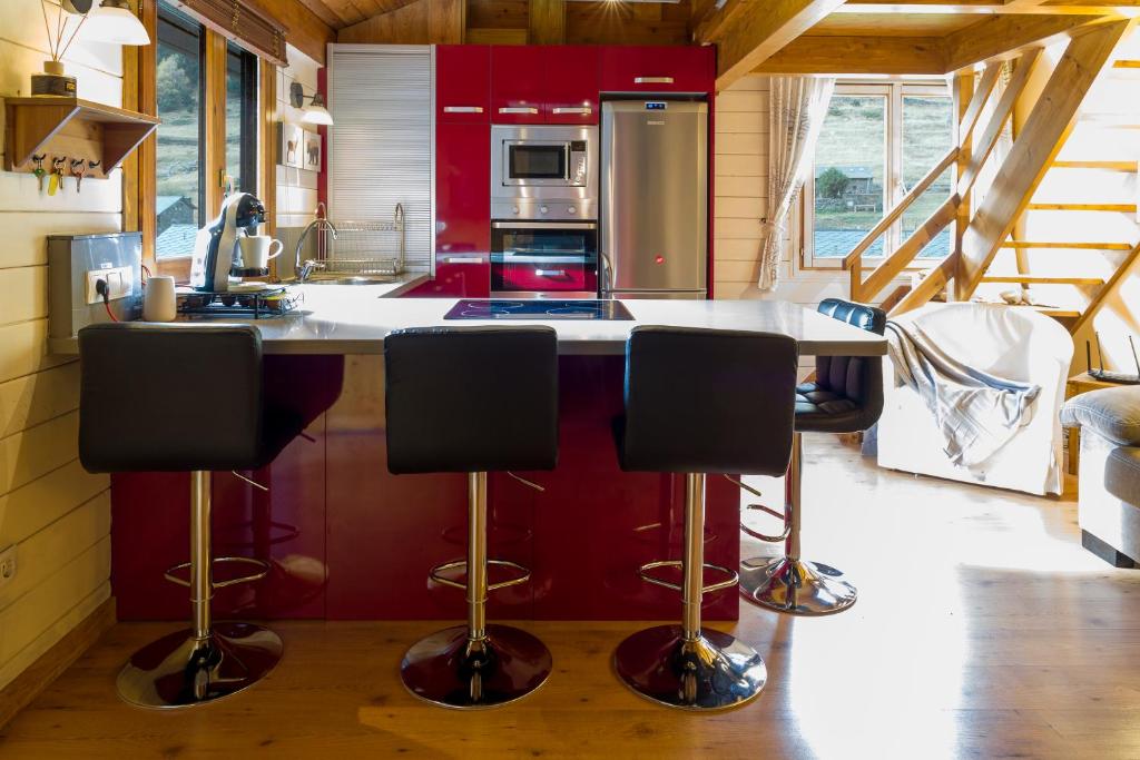卡尼略AndBnB I Duplex Rustico en Plena Naturaleza I Parking Gratis的厨房配有红色橱柜和带吧台凳的台面