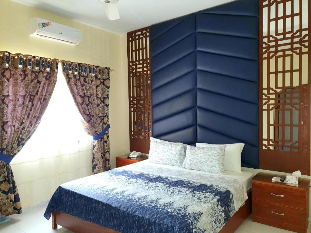 卡拉奇Hotel Imperial Karachi的一间卧室配有蓝色床头板和一张床