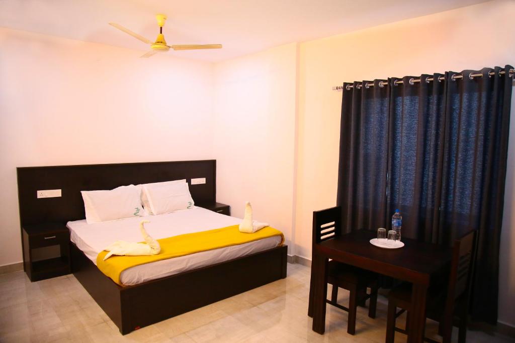 提喀迪Thekkady Travel Rooms的一间卧室配有一张带黄毯和桌子的床