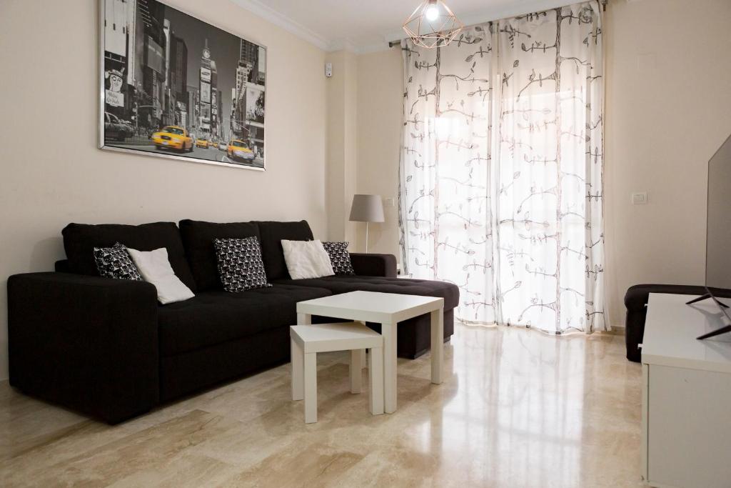 马拉加Apartamento Málaga Jalón的客厅配有黑色沙发和桌子