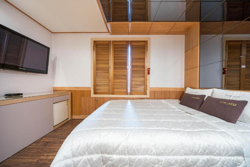 釜山MU Hotel Sasang的卧室配有一张白色大床和一台平面电视。