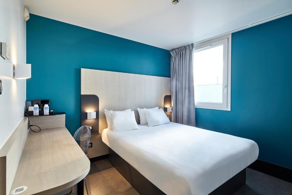 戈内斯B&B HOTEL Paris Nord Gonesse Parc des Expos的酒店客房设有一张大床和蓝色的墙壁。