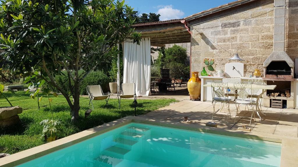 米内尔维诺迪莱切B&B Masseria Dei 12 Granai的庭院内的游泳池,配有桌椅