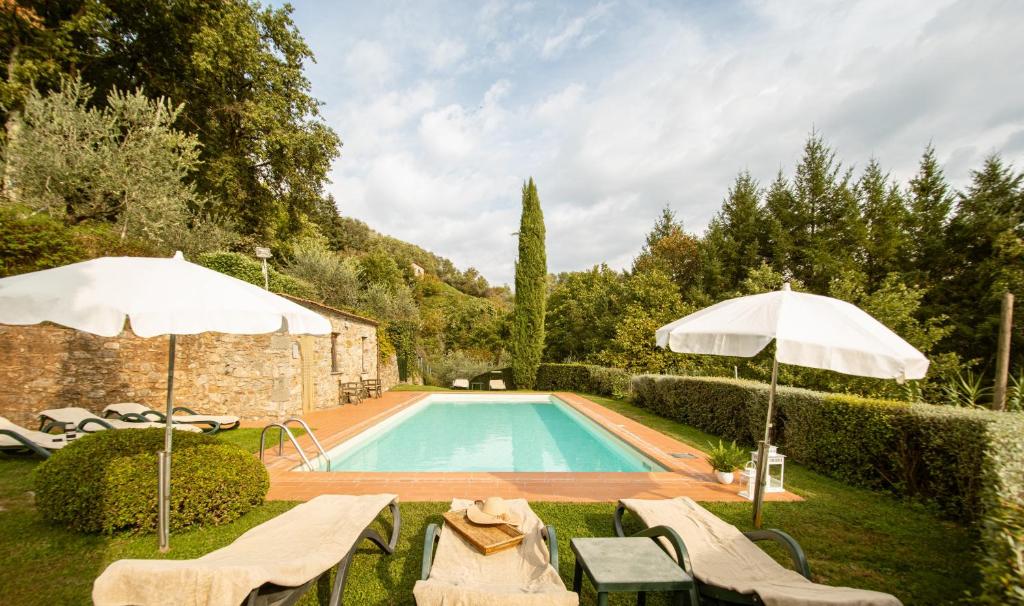 卢卡Casetta di Butia, Appartamento Iris的庭院内一个带椅子和遮阳伞的游泳池