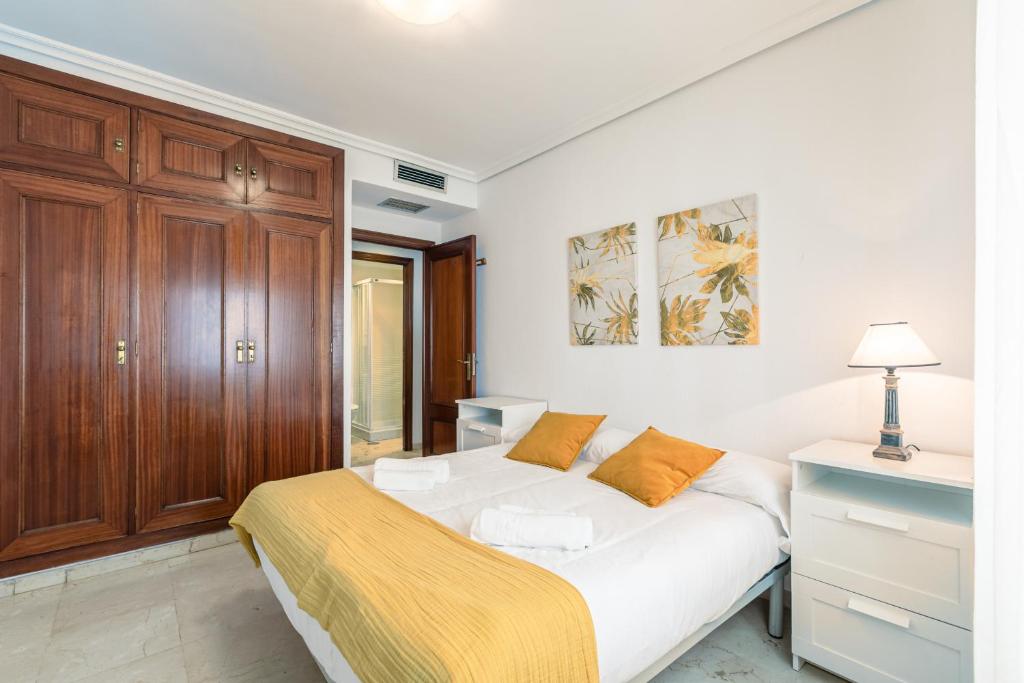 塞维利亚Green- Apartments Las Setas的卧室配有白色的床和木制橱柜。