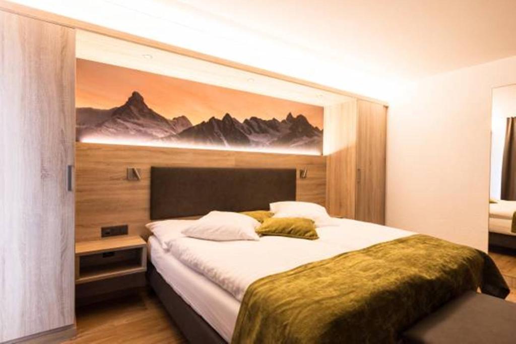 采尔马特布里斯都酒店的卧室配有一张大床,墙上挂有绘画作品
