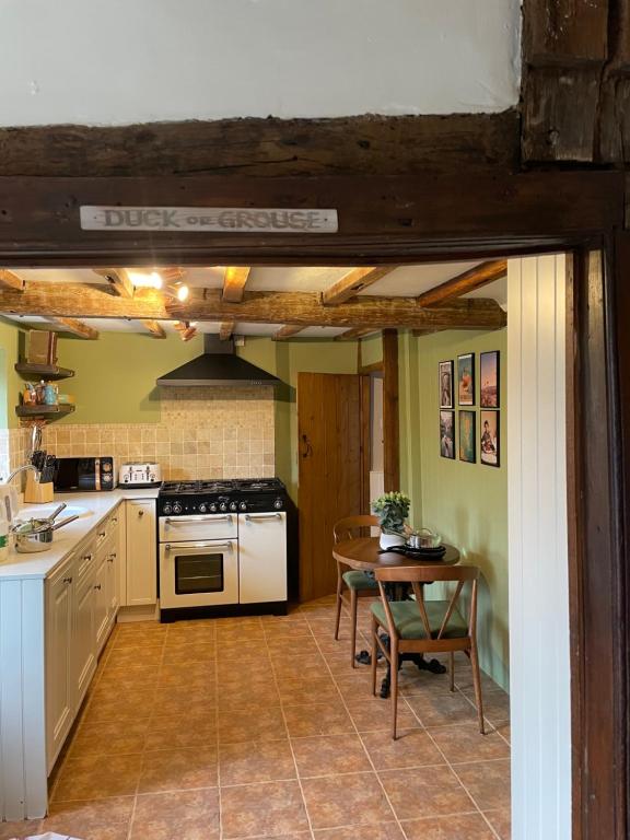 BridgeArms Cottage的厨房配有桌子和炉灶。 顶部烤箱