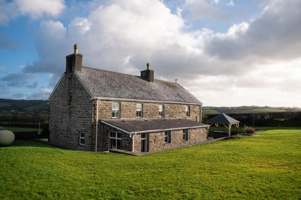 卡马森Castell Y Waun- Beautiful and spacious country farmhouse with luxury Hot Tub & Grounds的草地上的旧砖房