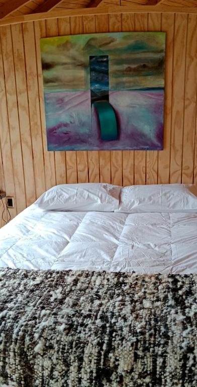 YutuyWillipeuma的卧室内的一张床铺,墙上有绘画作品
