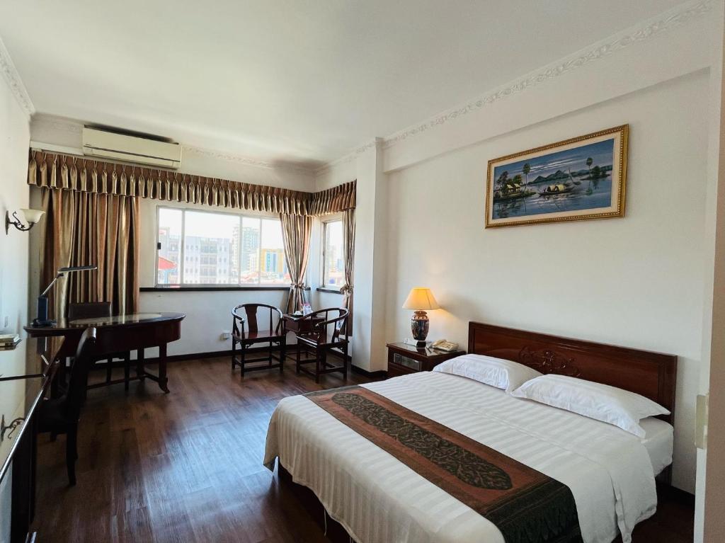 金边Chung Hsin Hotel 中信酒店的酒店客房设有一张大床和一张书桌。