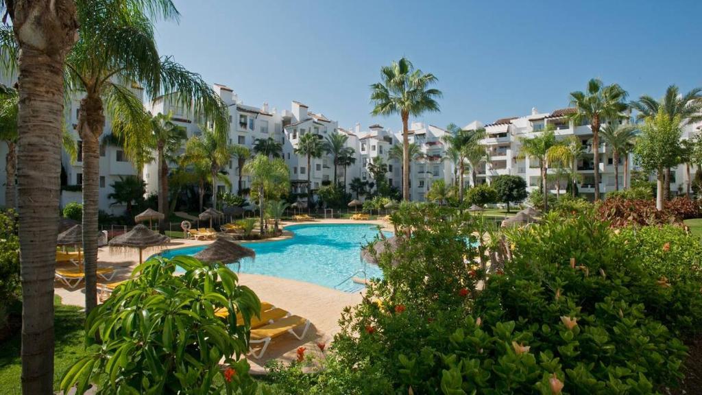 EsteponaCostalita on the Beach - 3 bedroom cosy apartment的一个带游泳池和棕榈树的度假村