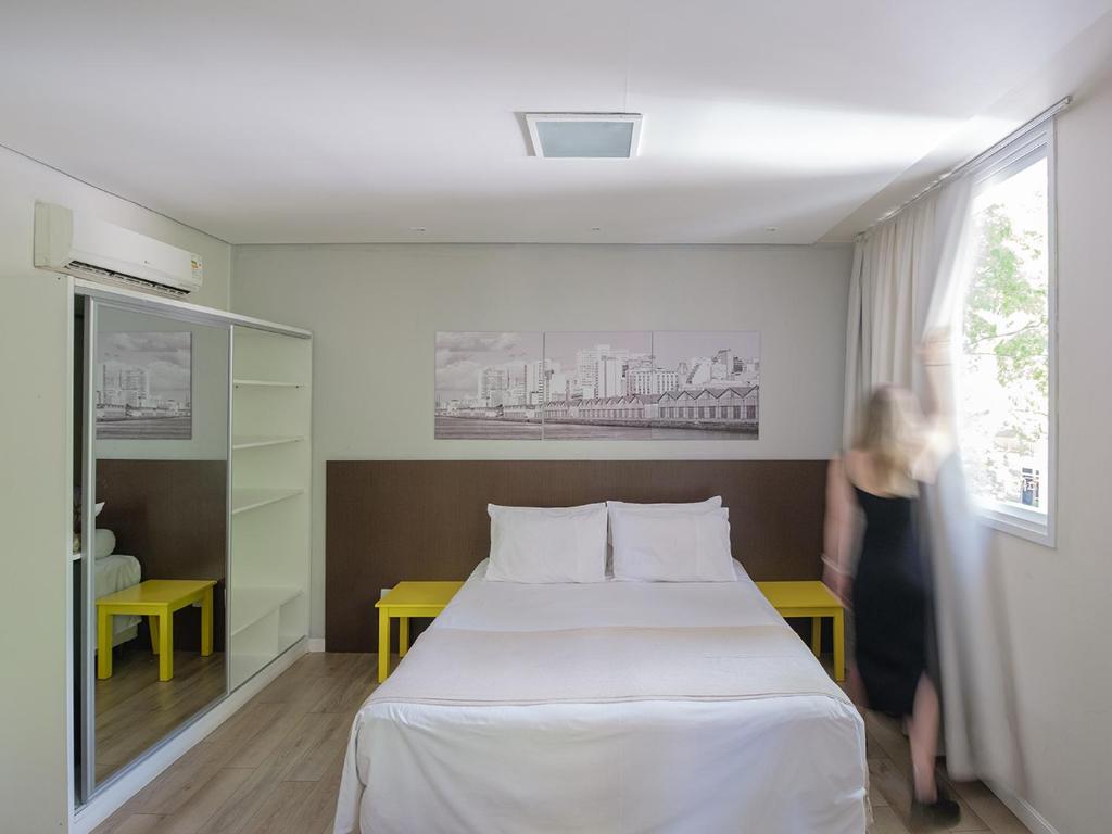 阿雷格里港Açores Flat Design- Ao lado da Casa De Cultura Mário Quintana的站在房间床边的女人