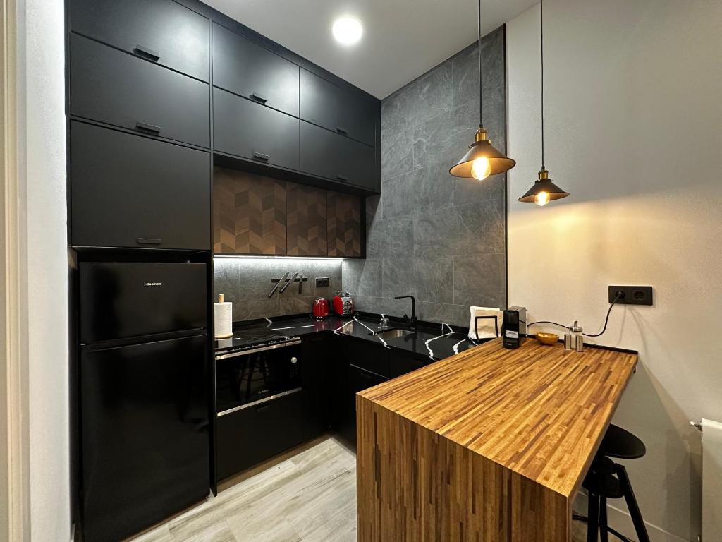 马德里CC Atocha Apartments的厨房配有黑色冰箱和木制柜台。
