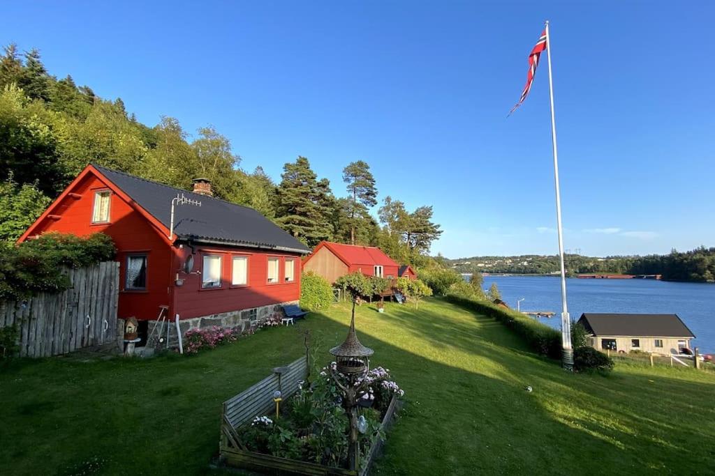 法尔松Hytte at Oyvoll in Farsund的山上的红色房子,有旗帜