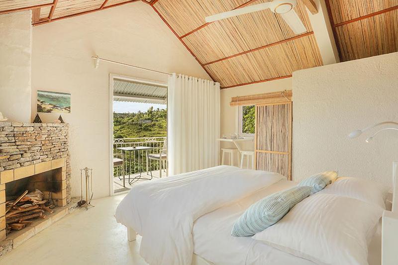 Rodrigues IslandFantaisie Lodges的一间白色卧室,配有一张床和一个壁炉