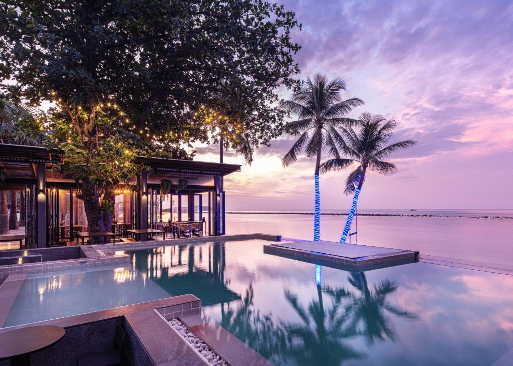 查汶Lub d Koh Samui Chaweng Beach的一座拥有两棵棕榈树和房子的游泳池