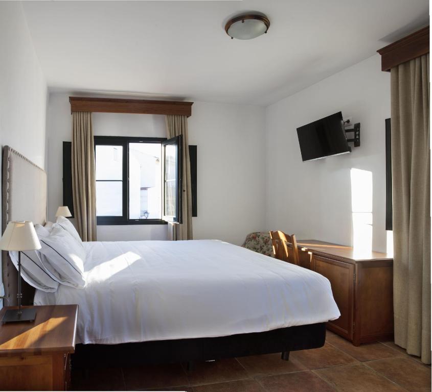 奥尔维拉Hotel Tugasa Sierra y Cal的卧室配有白色的床、书桌和窗户。