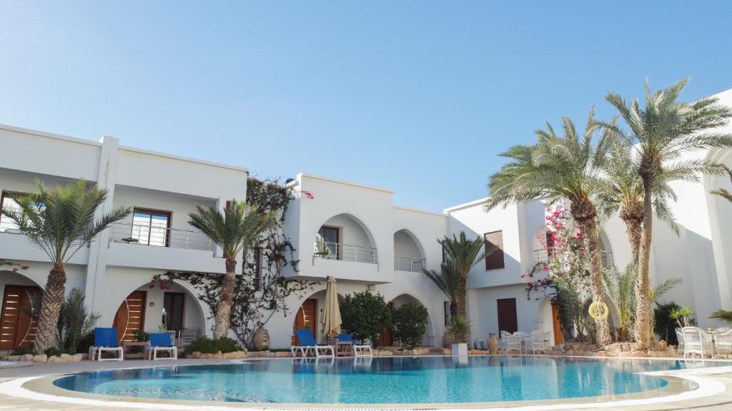 迈来亚Palm Djerba Suites的一座拥有游泳池和棕榈树的酒店