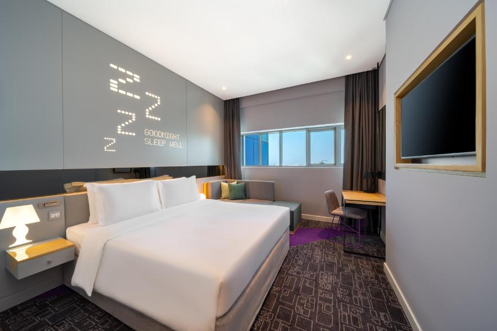 迪拜Studio M Al Barsha Hotel by Millennium的一间酒店客房,配有白色的床和一台平面电视