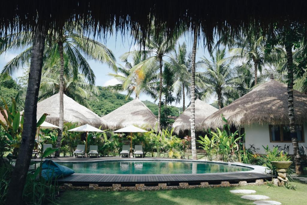 龙目岛库塔Mana Eco Retreat的棕榈树度假村前的游泳池