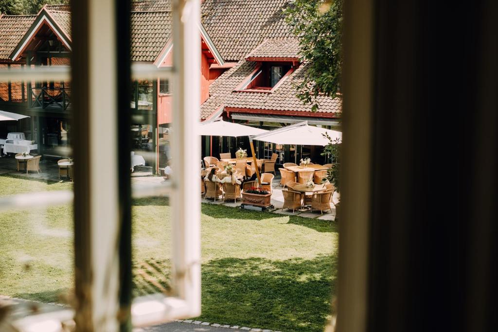 彻默岛Engø Gård Hotel & Restaurant的享有庭院景致的窗户,配有桌子和遮阳伞