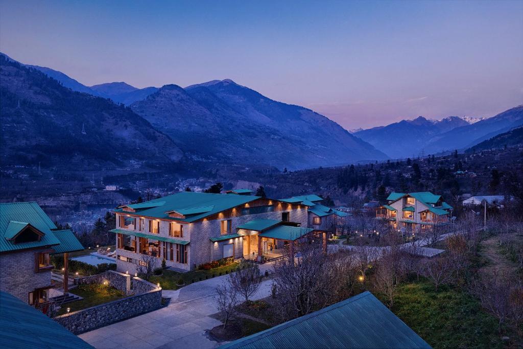 马拉里Baragarh Resort & Spa, Manali- IHCL SeleQtions的一座大房子,背景是群山