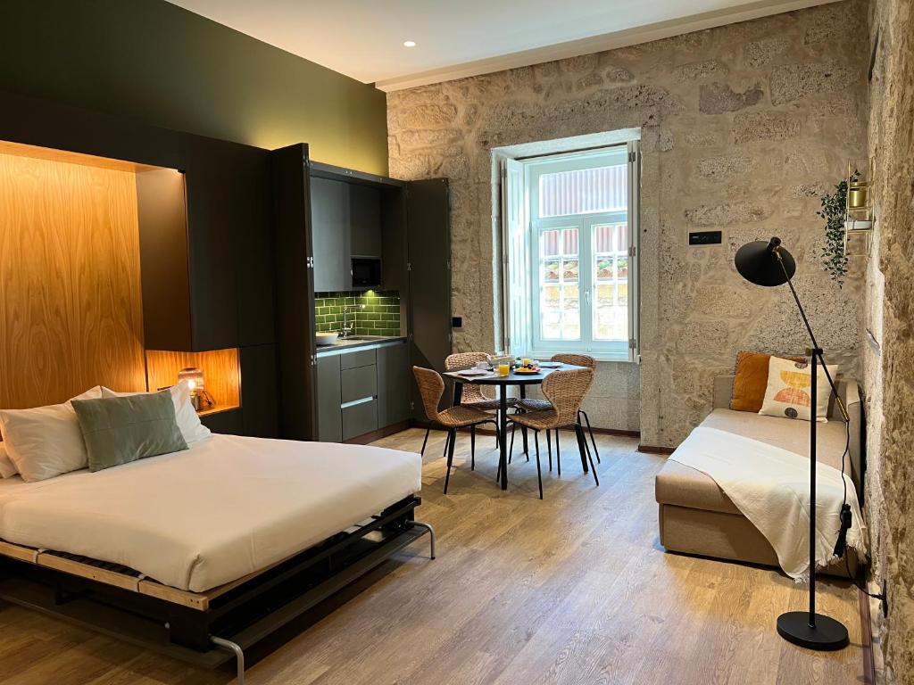 波尔图Oca Ribeira do Porto AT的一间卧室配有一张床铺和一张桌子,还设有一间厨房
