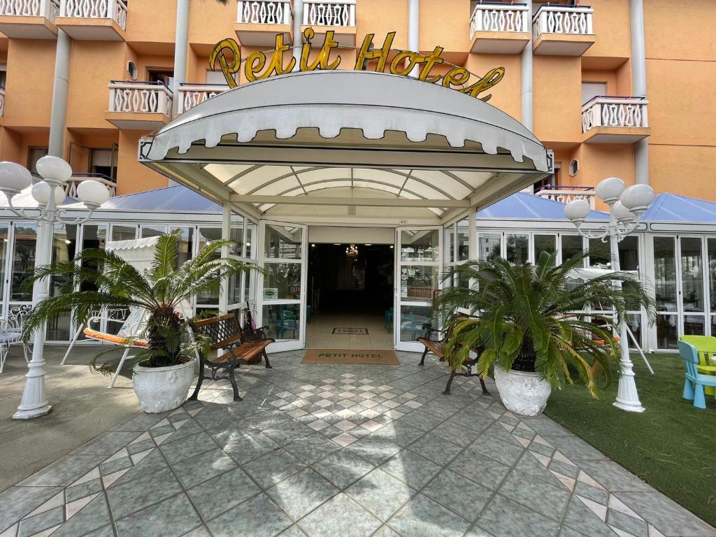 卡奥莱Petit Hotel的酒店大楼设有长椅和棕榈树庭院