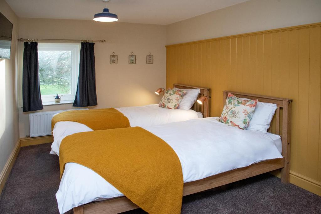牛顿艾克利夫Stay Northside - Luxury Corporate & Leisure Stays Cottage, County Durham的黄色墙壁客房的两张床