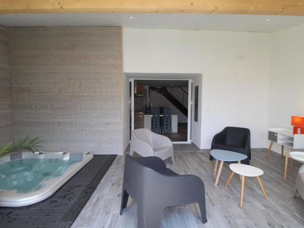 SavasGîte de Laphine avec Spa Privé的客厅设有按摩浴缸和椅子